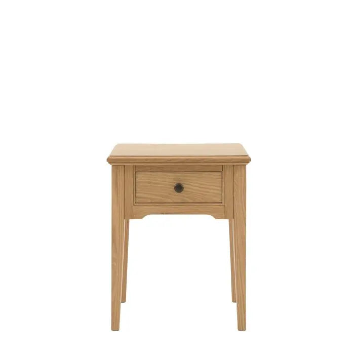 Gallery Direct Malvern Side Table features 1 drawer with metal handle and is crafted from quality oak solids and veneers with wood grain effect and slim tapered legs