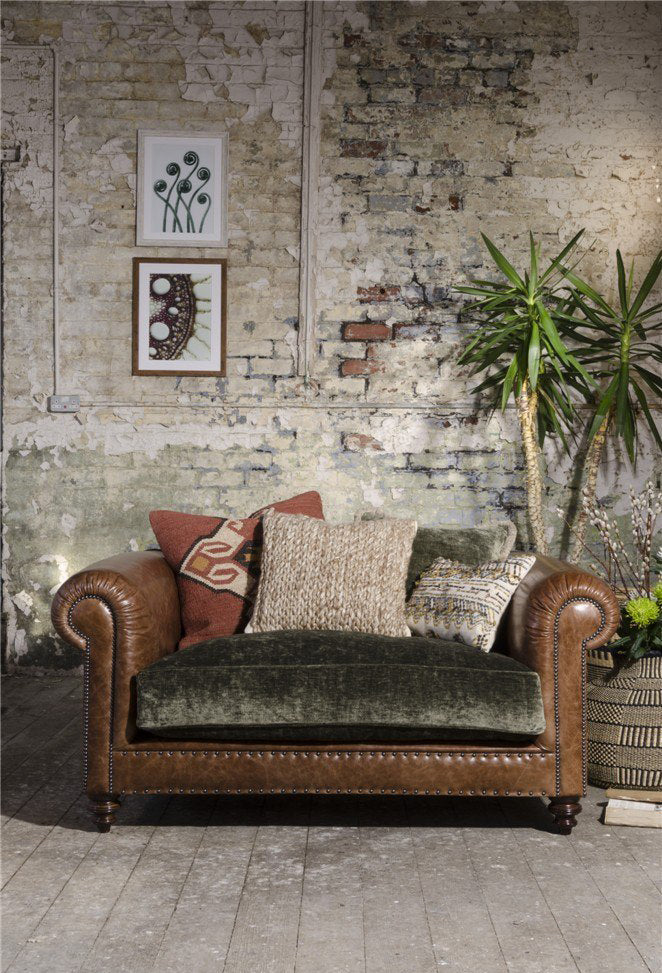 Tetrad Constable Snuggler Sofa handcrafted from Galveston Bark Leather with brass stud detailing and dark wood turned feet. Upholstered seat cushion in a sage green velvet and complemented by coordinating scatter back cushions