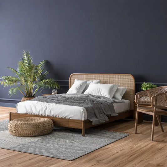 Scandi-style bedroom with rattan bed frame, dark grey wall and indoor plants