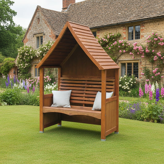 AFK Garden Products Goodwood Arbour in Beech Stain, has a traditional shape with high roof, enclose back and a slatted seat 