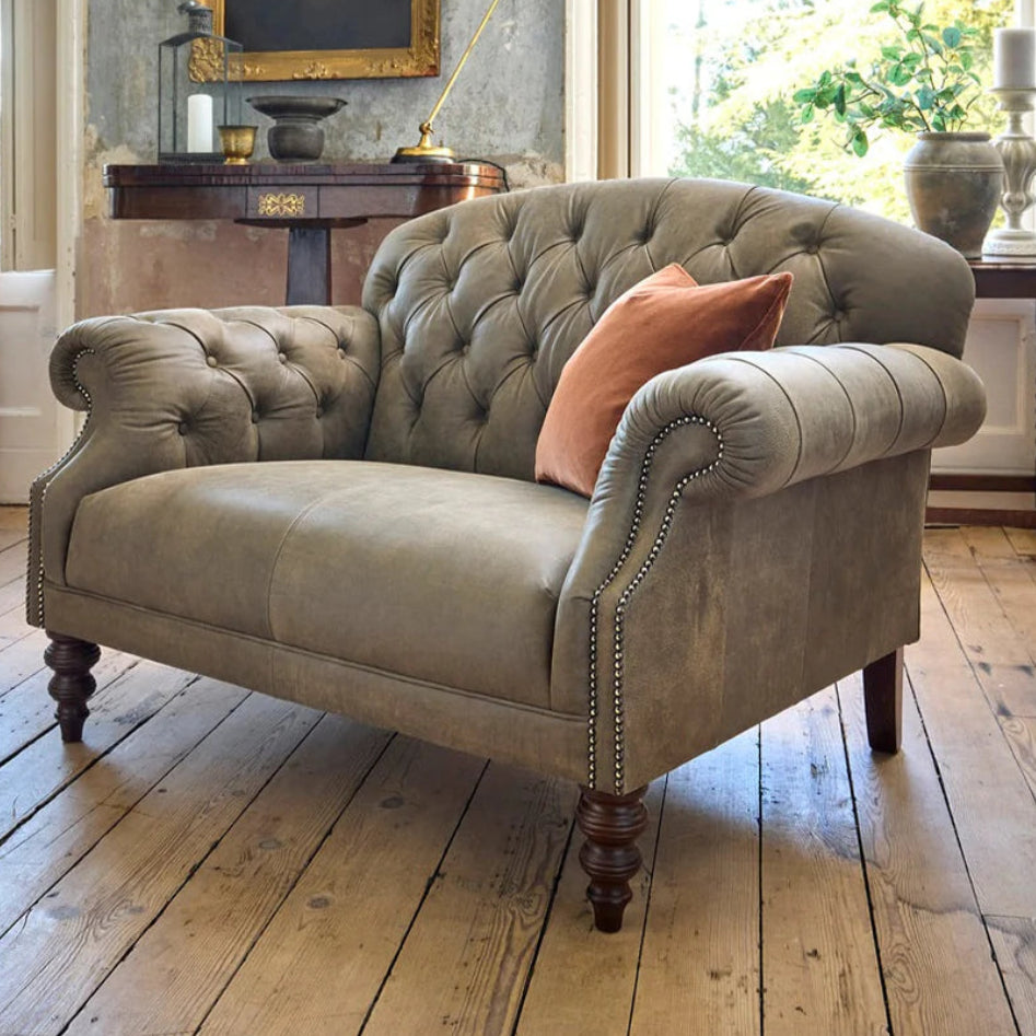 Tetrad Arbroath Snuggler Sofa in Commanche Timber Leather Hide, with deep button tufting to the classic chesterfield inspired design, scrolled arms with stud detailing and dark wooden legs