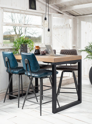 The Baker Dalton Bar Chair in Dark Blue quilted faux leather upholstery, features a 180 degree swivel seat, and powder coated metal legs with footrest bar