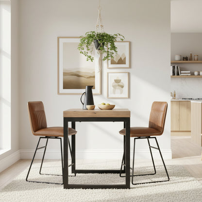 The Baker Cooper Pair of Bar Chairs in Tan faux leather upholstery, features a car seat inspired stitched design on the backrest, a comfortable padded seat and black tubular metal legs with footrest bar 