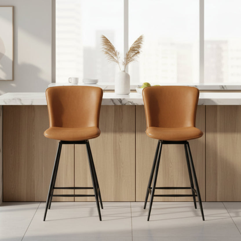 The Baker Pair of Ella Swivel Bar Chairs are upholstered in Tan faux leather, with black metal legs