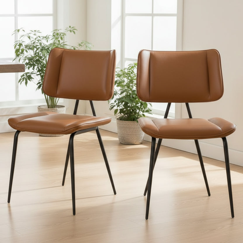 The Baker Pair of Jack Dining Chairs upholstered in a Cognac Tan coloured PU leather, with black powder coated metal legs and frame