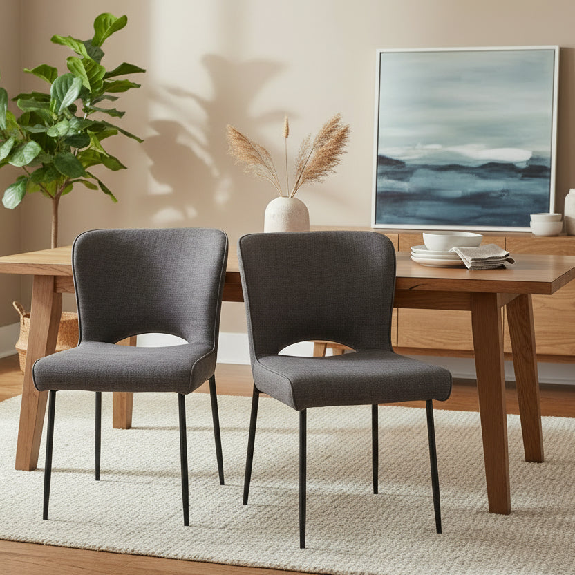 The Baker Pair of Maya Dining Chairs are upholstered in a Dark Grey linen fabric with PU piping detail and black metal legs