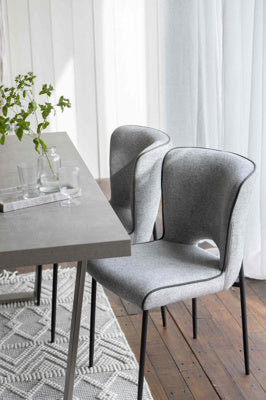 The Baker Pair of Maya Dining Chairs upholstered in a Light Grey linen fabric with PU piping detail and black metal tubular legs