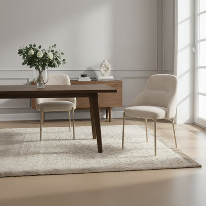 The Baker Pair of Quinn Dining Chairs are upholstered in a neutral coloured boucle style, textured fabric with pale gold colour coated metal legs