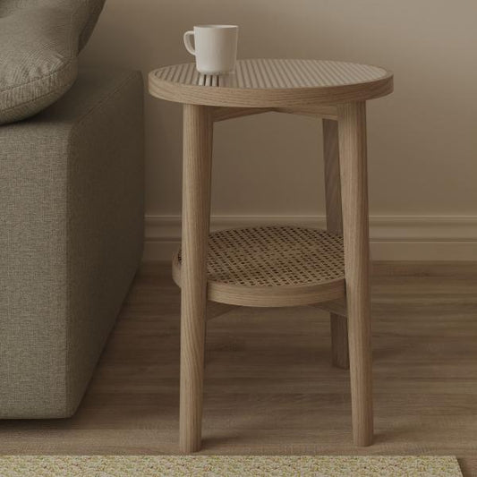 Carlton Furniture Holcot Rattan Side Table features a natural oak wood frame, a round glass top and lower rattan shelf
