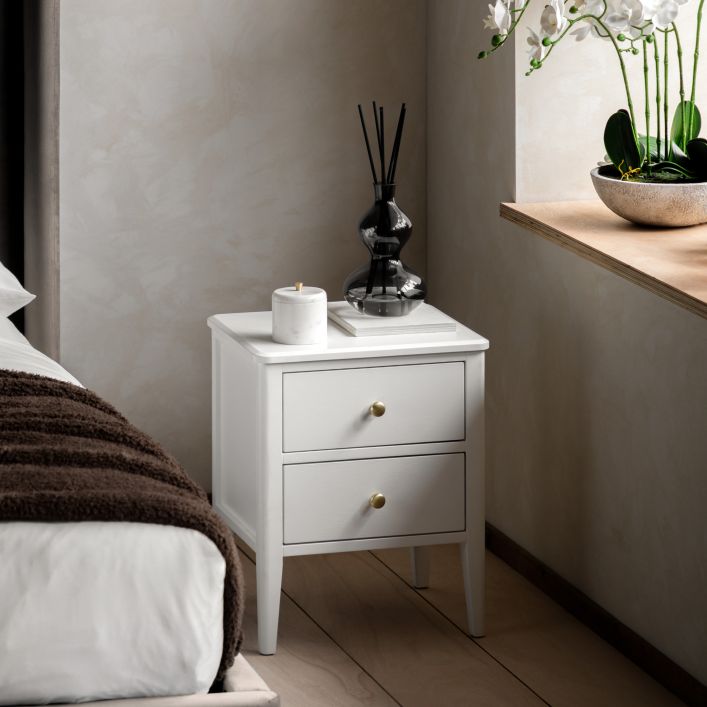 Gallery Direct Acton Bedside Table in White features 2 drawers with round gold coloured handles. and slim tapered legs