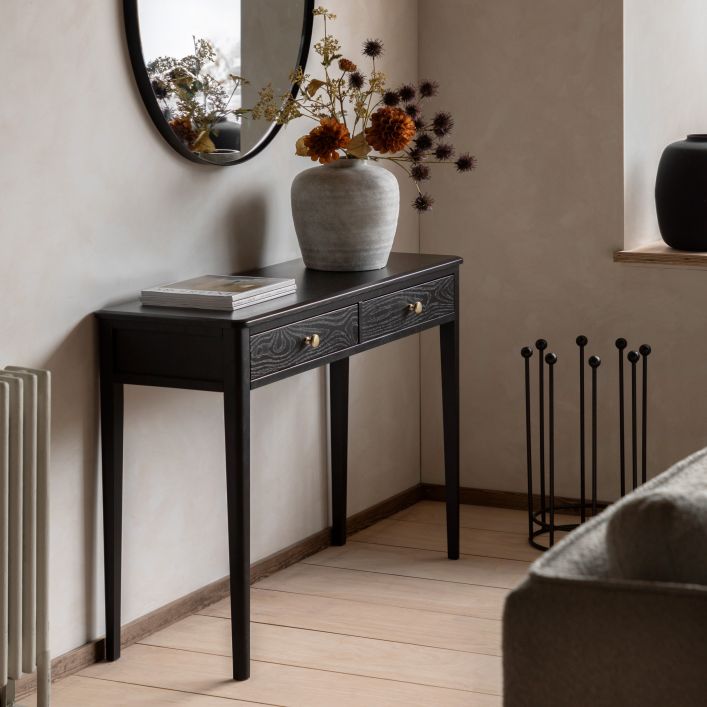 Gallery Direct Acton Black Console Table features 2 drawers with gold coloured handles, wood-grain effect and slim tapered legs