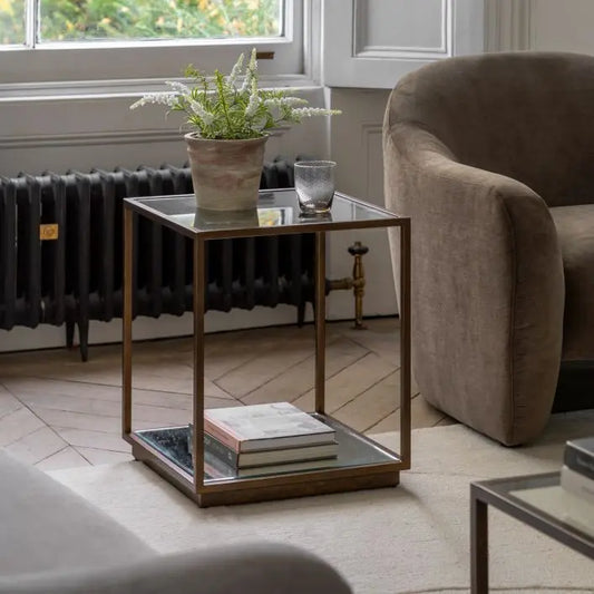The Gallery Direct Avento Side Table features a bronze colour metal frame and glass table top with lower glass shelf