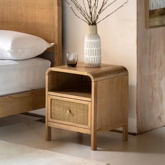The Gallery Direct Bibury Bedside Cabinet features 1 drawer with rattan detailing and an upper shelf for extra storage. Crafted from oak and pine wood and veneers with a soft lime wash finish and curved edges