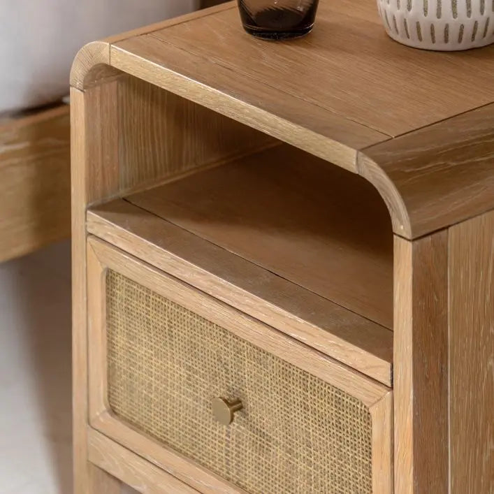 Gallery Direct Bibury 1 Drawer Bedside cabinet crafted from oak and pine wood and veneers with a soft lime washed finish. Rattan detail to the drawer front with a bronzed metal handle and an upper shelf for extra storage