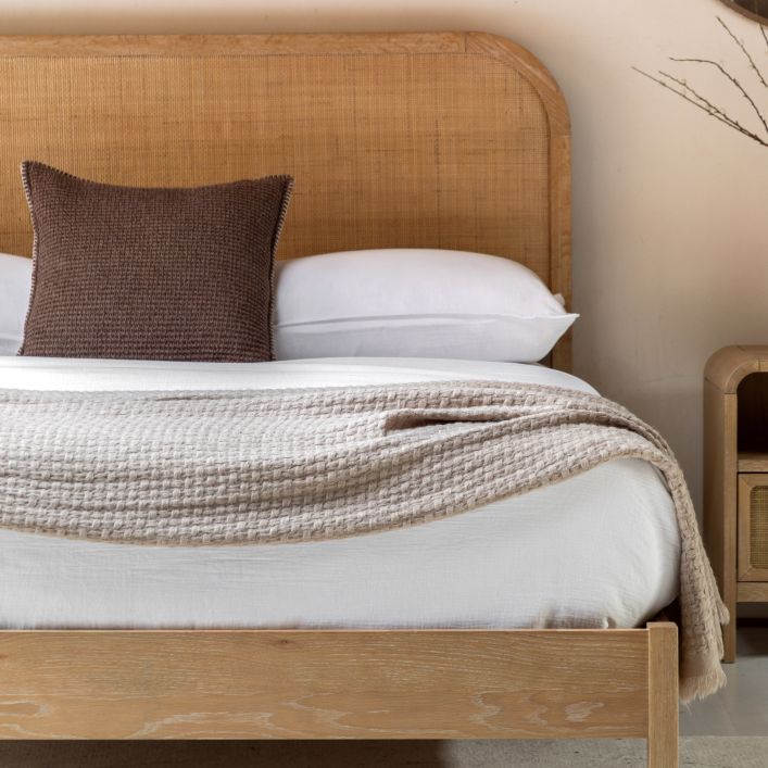 Gallery Direct Bibury Double Bed features a soft lime washed wooden frame and a gently curved rattan headboard