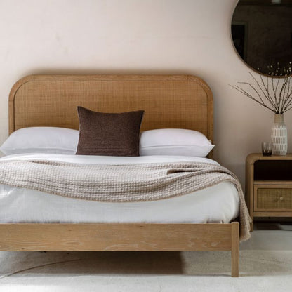 The Gallery Direct Bibury King Size Bed features a oak and pine wooden frame with a soft lime washed finish, and a rattan headboard 