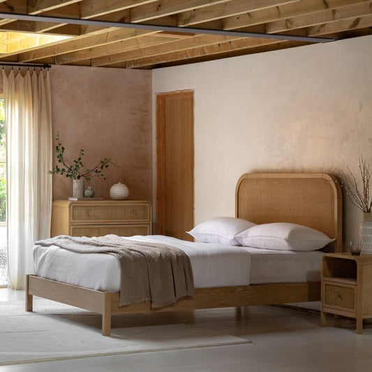 The Gallery Direct Bibury King Size Bed is crafted from oak and pine wood and veneers in a soft lime wash finish, with a curved rattan headboard for an elegant silhouette