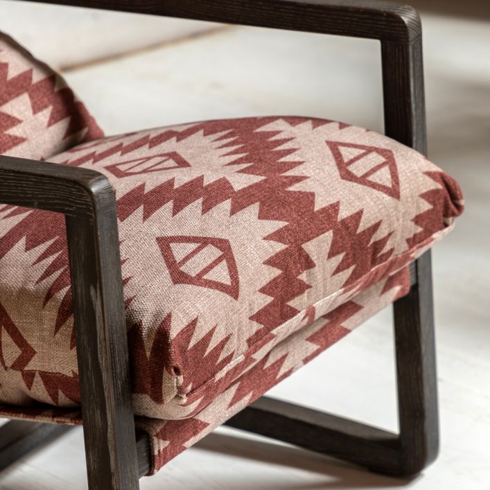 Gallery Direct Burela Lounge Chair in a padded red and natural coloured fabric with a Mira Aztec style design. The frame is made from a sturdy dark ash wood frame