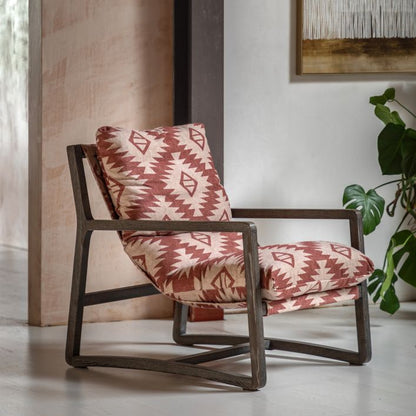 Gallery Direct Burela Chair is a padded lounge seat in red and natural coloured fabric with a Mira Aztec pattern, and a sturdy dark ash wood frame