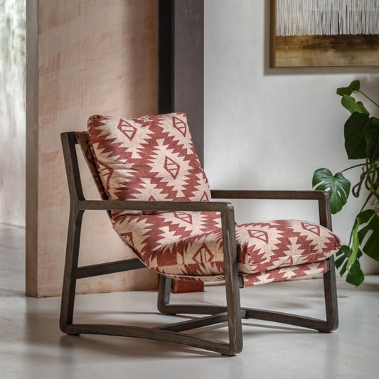 Gallery Direct Burela Chair is a padded lounge seat in red and natural coloured fabric with a Mira Aztec pattern, and a sturdy dark ash wood frame