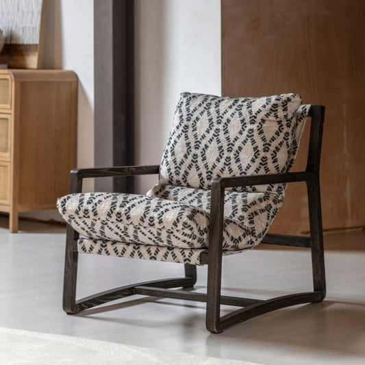 The Gallery Direct Burela Chair is a comfortable padded lounge seat in navy/natural coloured Obi Diamond pattern, with a rich dark ash wood frame