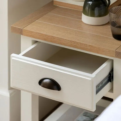 Gallery Direct Eton 1 Drawer Bedside Cabinet features a natural oak effect grooved table top, and a white wooden frame with metal handle and lower shelf 