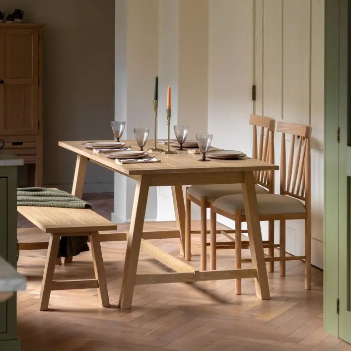 Gallery Direct Eton Extending Trestle Dining Table can seat up to 6 people and features a grooved table top and trestle style legs in a Natural oak finished wood