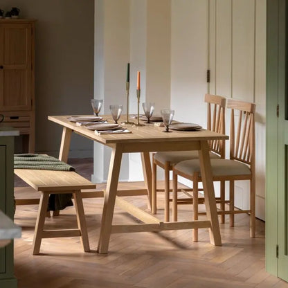 Gallery Direct Eton Extending Trestle Dining Table can seat up to 6 people and features a grooved table top and trestle style legs in a Natural oak finished wood