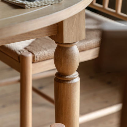 Gallery Direct Eton Round Extending Dining Table with a grooved table top an turned wooden legs constructed from Natural Oak wood and veneers