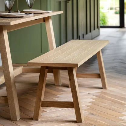 Gallery Direct Eton Trestle Bench in Natural oak woods and veneers, features a grooved planked top seat and trestle legs