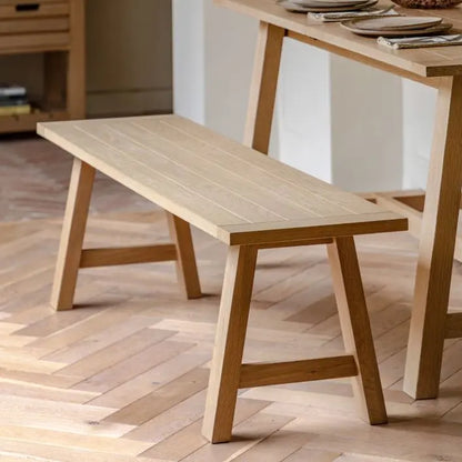 Gallery Direct Eton Trestle Bench in Natural oak wood and veneers with a planked and grooved seat that can accommodate 2-3 people