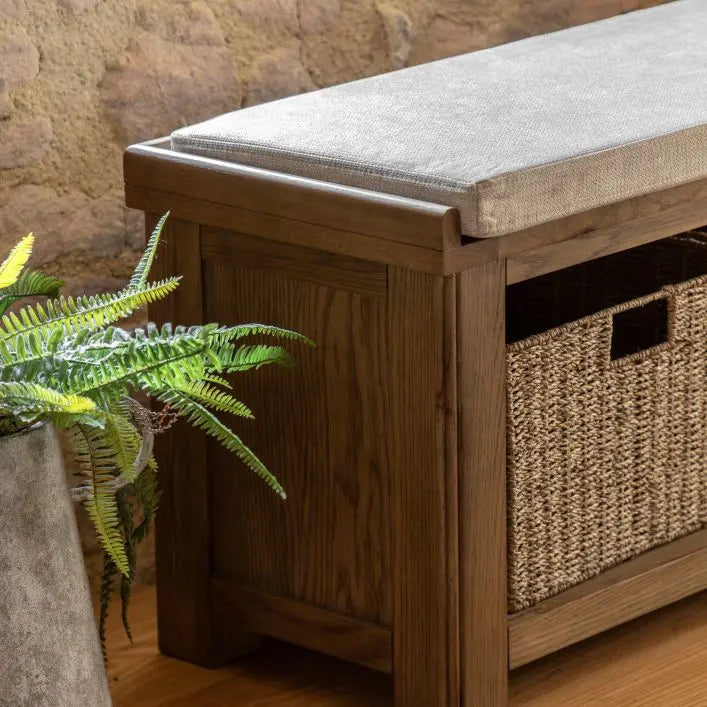 Gallery Direct Hardwick Hall Bench crafted from a sturdy oak and veneer wood frame, with a natural coloured padded seat cushion, and 3 wicker storage baskets 