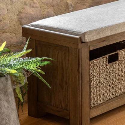 Gallery Direct Hardwick Hall Bench crafted from a sturdy oak and veneer wood frame, with a natural coloured padded seat cushion, and 3 wicker storage baskets 