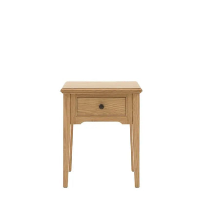Gallery Direct Malvern Side Table features 1 drawer with metal handle and is crafted from quality oak solids and veneers with wood grain effect and slim tapered legs