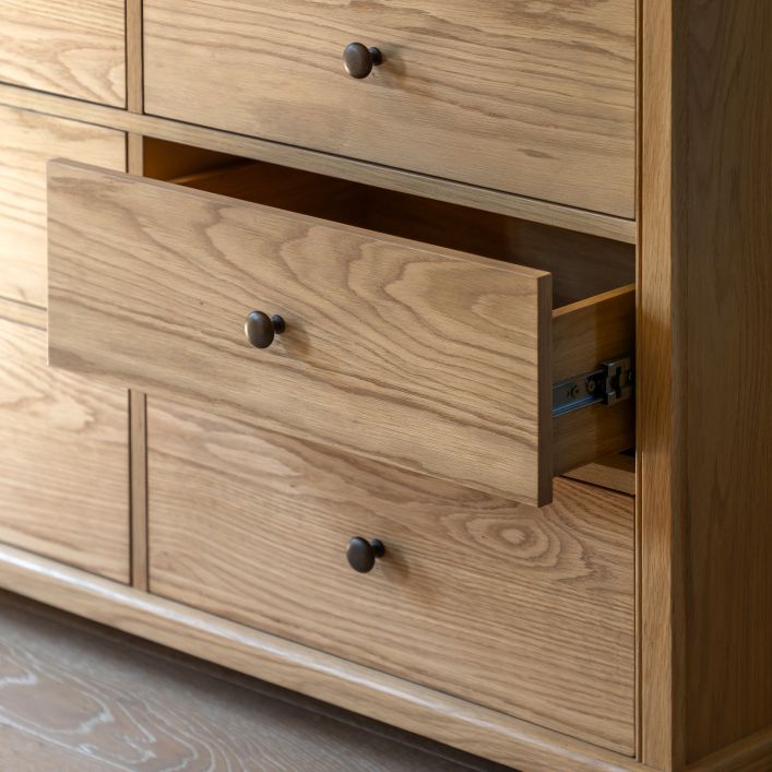 Gallery Direct Malvern 9 Drawer Chest is crafted from oak solids and veneers with distinctive wood-grain patterns and a warm natural finish, with dark metal knobs