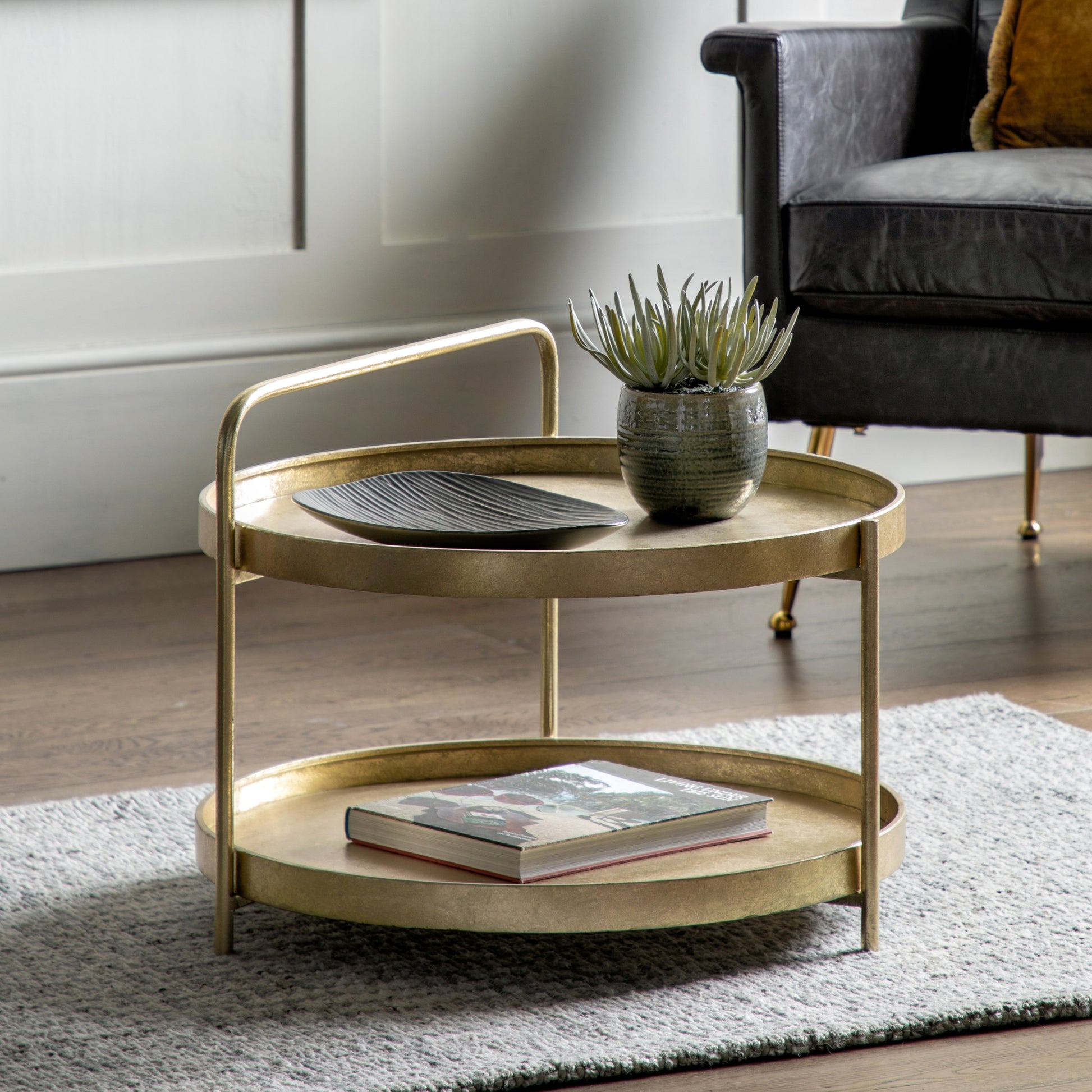 The Gallery Direct Sennen Metal Coffee Table has a distinctive tray-style table top and lower shelf with curved handle element in Gold leaf finish