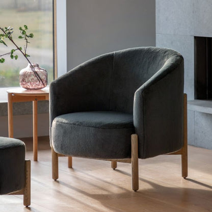The Gallery Direct Tindon Curved Armchair is upholstered in Alaska Graphite soft plush faux fur material with a solid wood base and legs