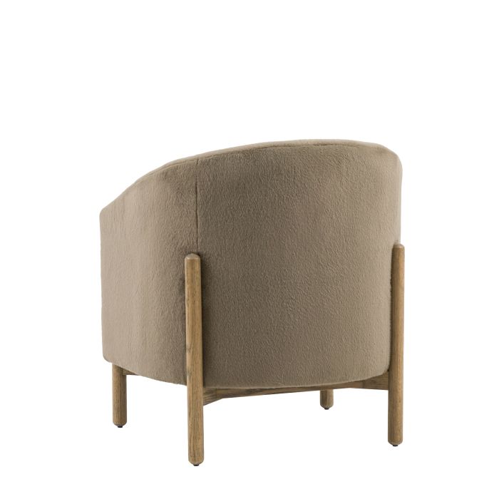 Gallery Direct Tindon Armchair is a curved chair upholstered in a soft plush Alaska Khaki colour faux fur, with solid wooden frame and legs