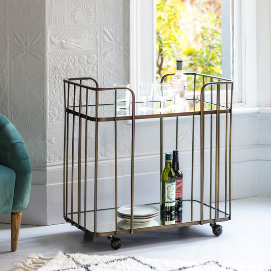 Gallery Direct Verna Drinks Trolley features a Bronze metal frame with toughened glass shelves and smooth rolling castors 