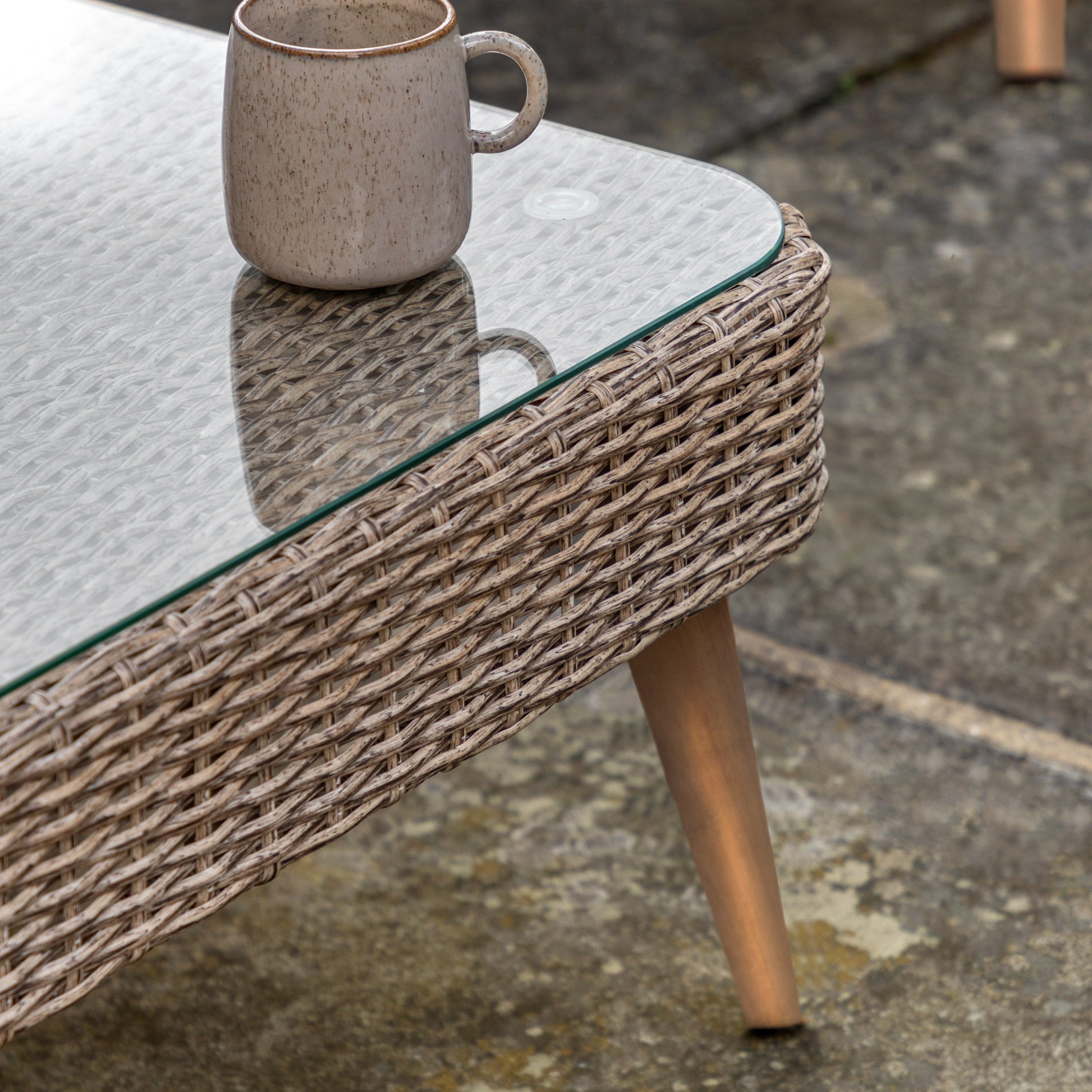 Gallery Garden Avena Corner Lounge Set features a corner sofa and matching coffee table with poly-rattan wicker style frame, a glass table top and oiled acacia wood legs