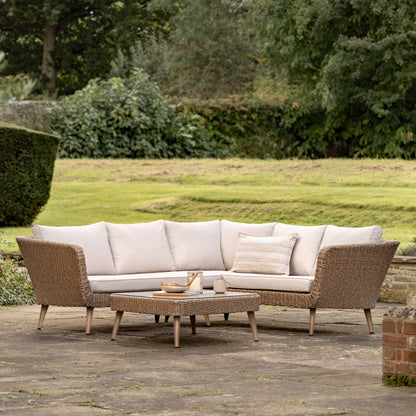 Gallery Garden Avena Corner Lounge Set features a 5 seater corner sofa and a matching glass top coffee table, with poly-rattan wicker frame and generously padded natural toned cushions