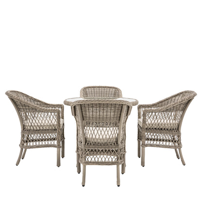Gallery Garden Menton Dining Set features a round glass topped table with underneath shelf, and 4 armchairs with padded seat cushions, crafted from stone coloured PE rattan and aluminium