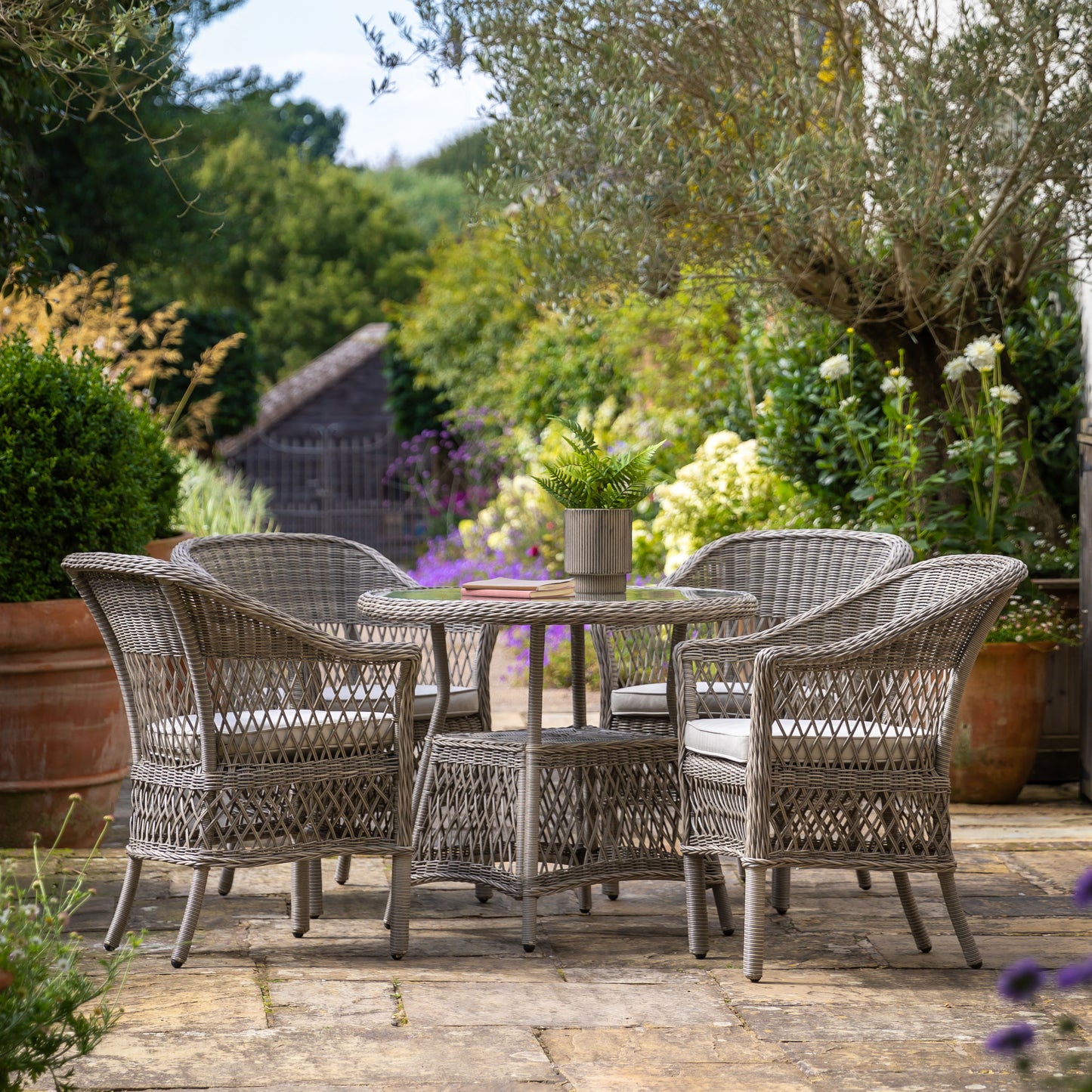 Gallery Garden Menton 4 Seater Dining Set in Stone coloured PE rattan with a glass topped table and 4 armchairs with cushions