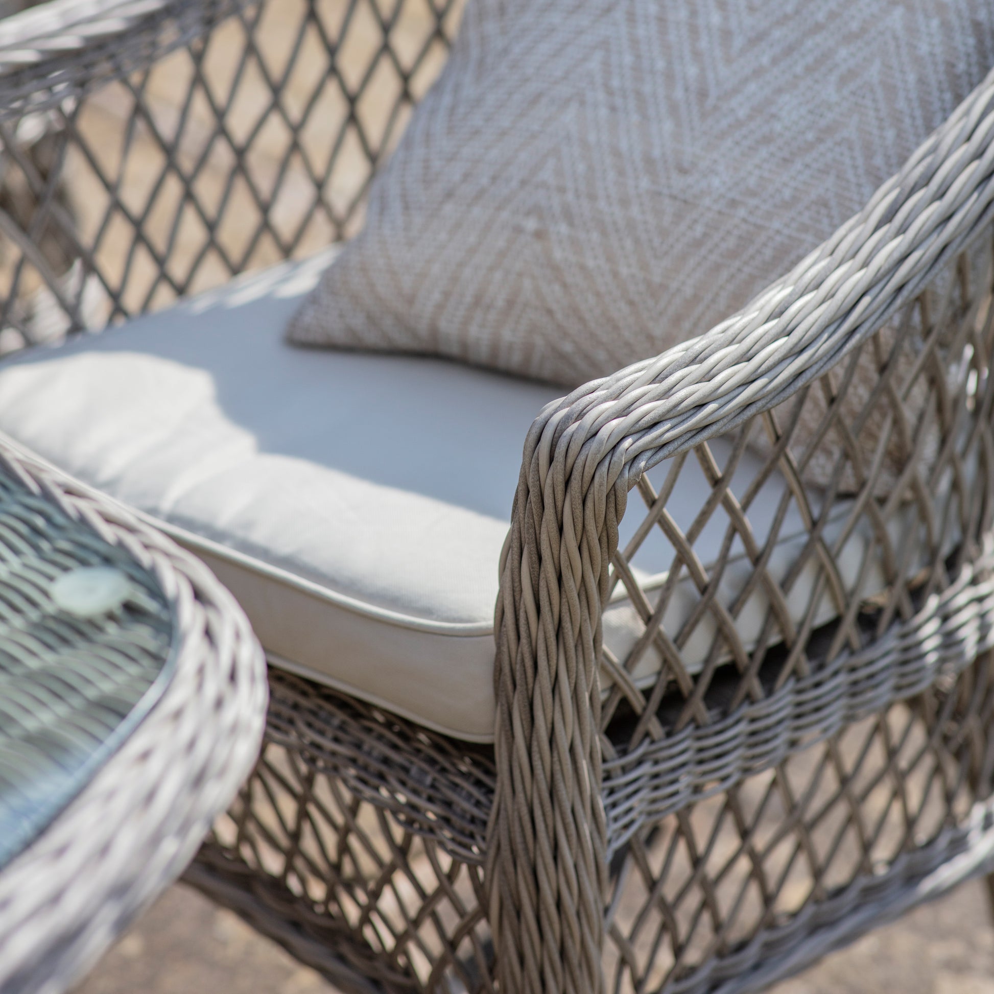 Gallery Garden Menton 6 Seater Oval Dining Set in Stone features 6 PE rattan armchairs with seat cushion, and a matching table with glass top