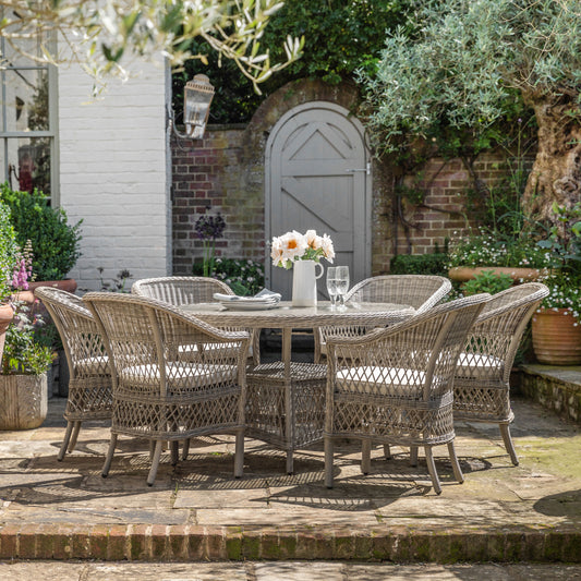 Gallery Garden Menton 6 Seater Round Dining Set features a glass topped table with an underneath shelf constructed in a stone colour PE woven rattan, and 6 matching armchairs with padded seat cushion