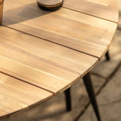Gallery Garden Ponza Round Dining Table crafted from a warm natural coloured acacia wood and dark metal legs