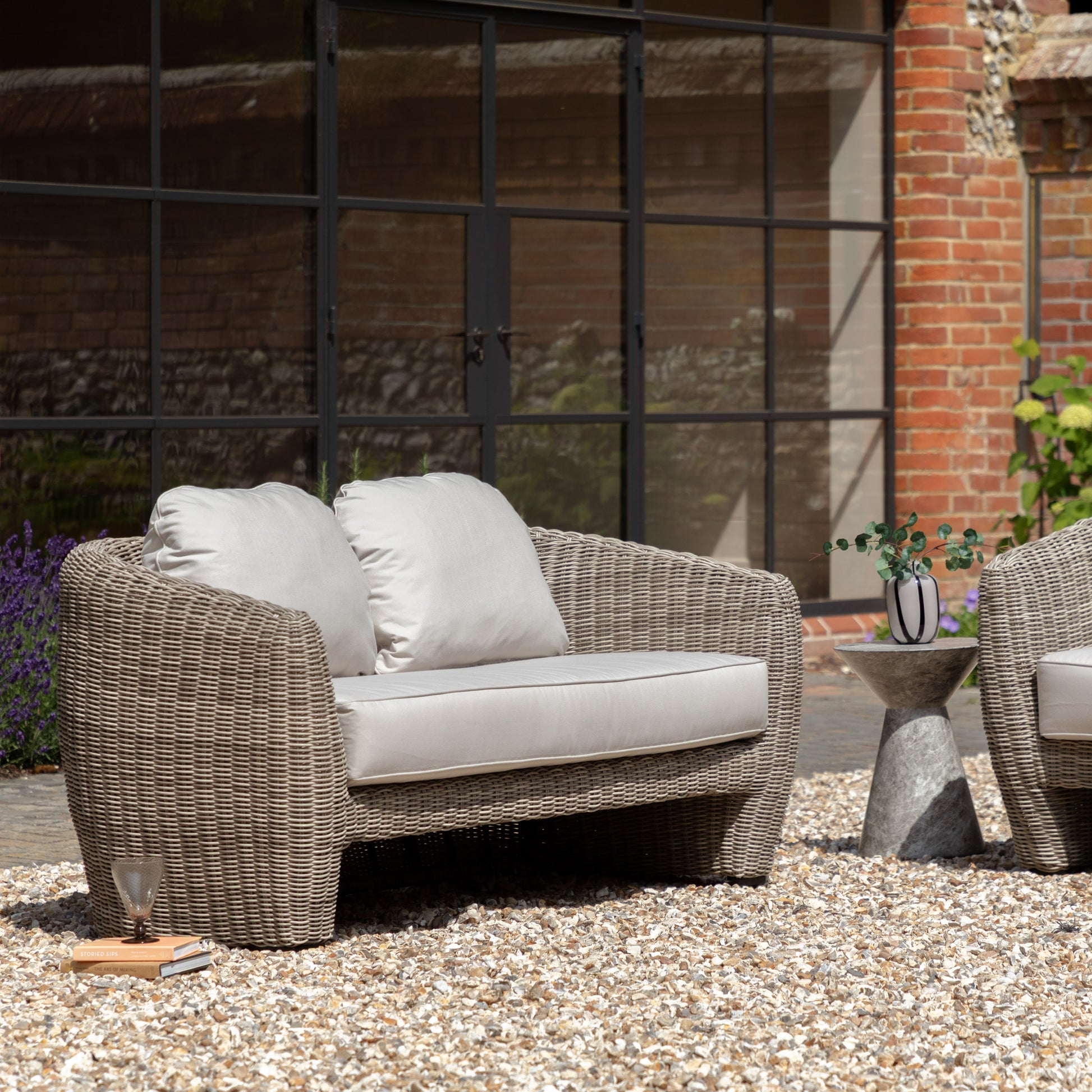Gallery Garden Positano 2 Seater Sofa featuring sleek curved lines and a sophisticated grey finish, crafted from weather-resistant woven wicker, with generously padded foam-filled cushions for exceptional comfort