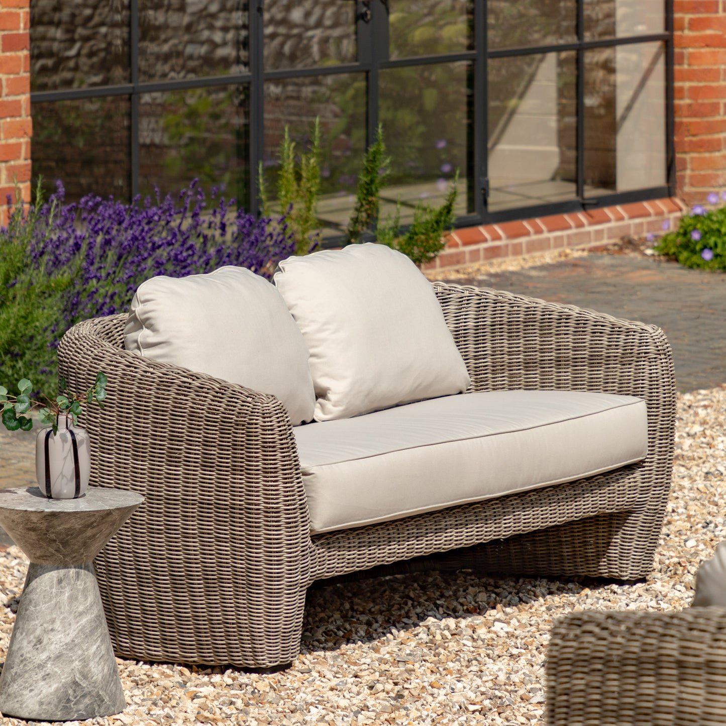 Gallery Garden Positano 2 Seater Sofa featuring sleek curved lines and a grey finish to the weather-resistant woven wicker, with generously padded foam-filled cushions for exceptional comfort.