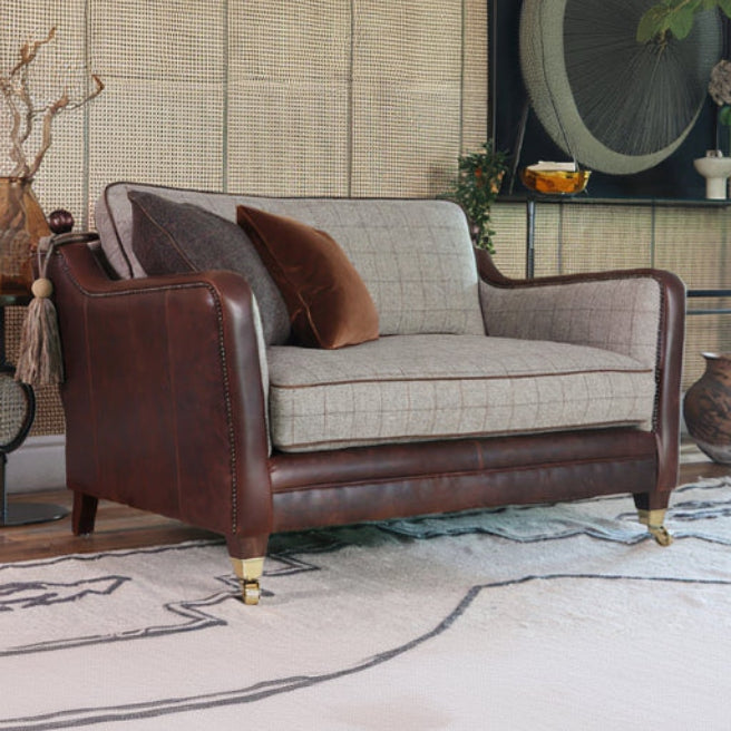 Tetrad Balmoral Snuggler Sofa in Austin Cumin Seed & Munro Check upholstery with rich brown leather panels with stud detailing, scatter cushions and wooden feet with castors
