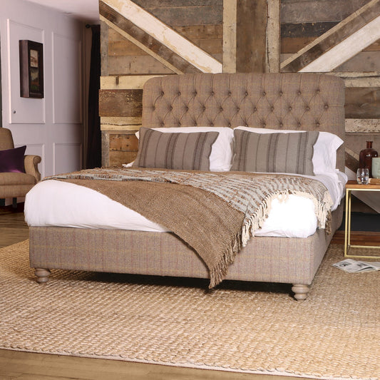 The Tetrad Berneray King Size Bed Frame is fully upholstered in Bracken Herringbone weave fabric, deep button tufted tall headboard and elegant turned wood feet, with a sprung slatted base